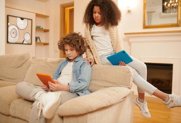 Online. A boy and a girl with devices watching something online