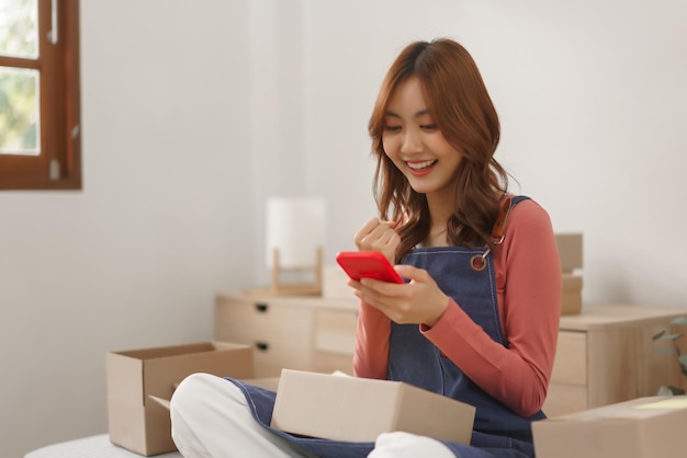 Концепция онлайн-бизнеса Женщины-предприниматели улыбаются и счастливы, получая заказ на смартфоне