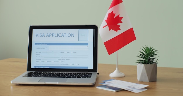 Online Canada Visa Application showing on a laptop computer screen sitting on a desk Travelling abroad or immigration concept