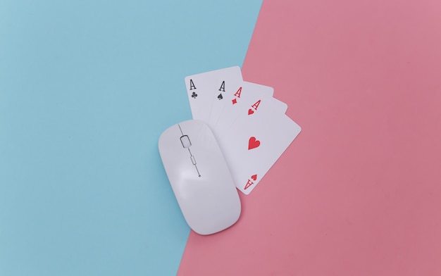 Online casino. Pc mouse and four aces on pink blue background. Top view