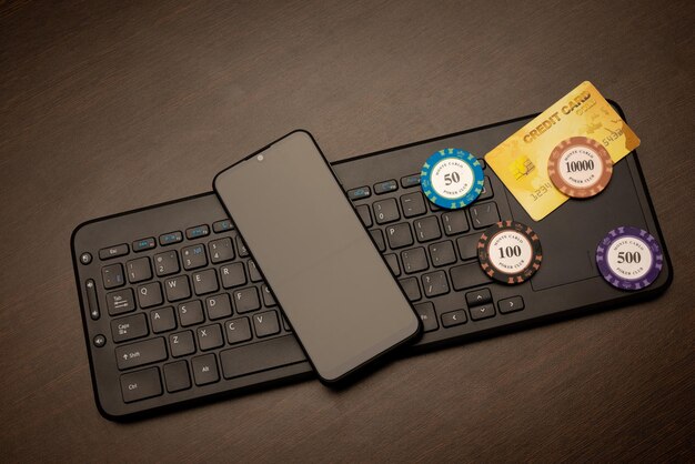 Online casino theme. Smartphone, credit card and poker chips lie on the computer keyboard