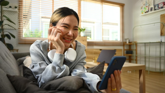 オンラインコミュニケーション自宅でスマートフォンを介してビデオ通話を行う幸せな若い女性