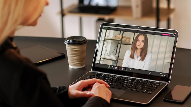 Foto donna d'affari sicura di sé in ufficio video per conferenze online che discute di partnership con una collega