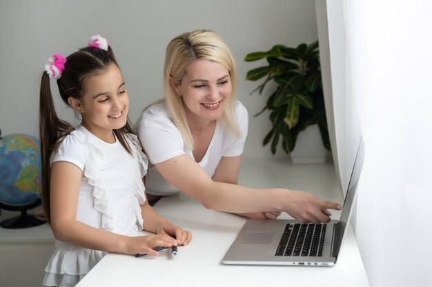 Online education of children. Mother and daughter of preschool watching a video lesson call chat creative course art drawing using lapott at home.