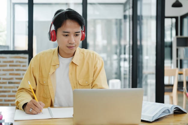 Online education elearning Young collage student using computer and mobile device studying online Asian young student online learning class study online video call zoom teacher