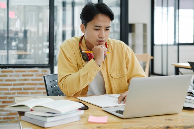 Online education elearning Young collage student using computer and mobile device studying online Asian young student online learning class study online video call zoom teacher