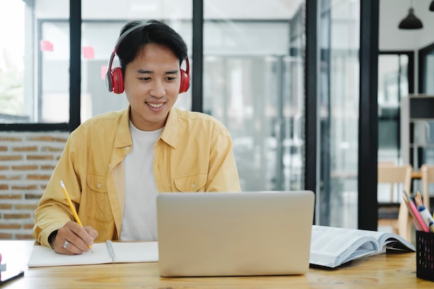 Online education elearning Young collage student using computer and mobile device studying online Asian young student online learning class study online video call zoom teacher