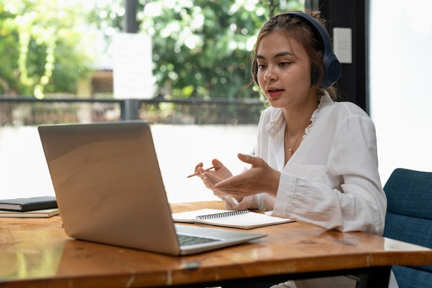 Foto formazione online elearning giovane donna che studia a distanza utilizzando un laptop ascoltando lezione online prendendo appunti mentre si è seduti a casa