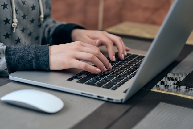 Online education. A girl prints text on a laptop at home at a computer. gray jacket