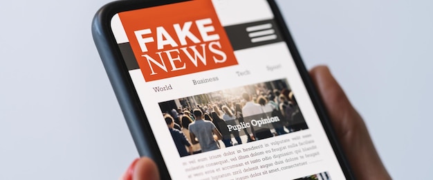 Online fake news on a mobile phone Close up of woman reading Fake news HOAX or articles in a smartphone screen application Hand holding smart device Mockup website Fake Newspaper portal