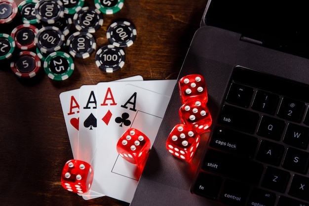 Online gambling concept red playing dice chips and cards on a wooden desk top view