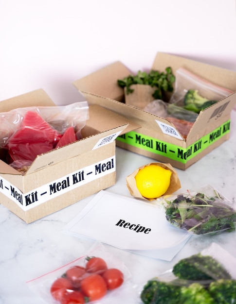 Online Home Food Delivery. Craft Box with packed tuna, shrimp, vegetables and recipe card on a kitchen background. Food delivery services during coronavirus pandemic and social distancing.