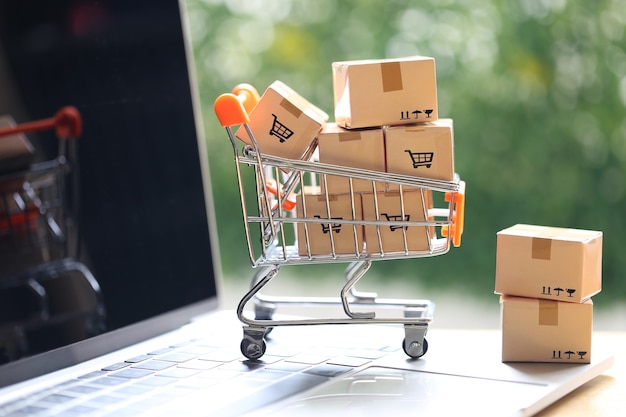 Online income,Brown parcel box and Model miniature shopping cart on computer keyboard for online shopping