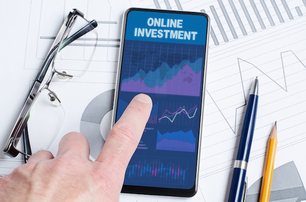 Photo online investment. a man is holding a smartphone with a mobile app with charts and graphs.