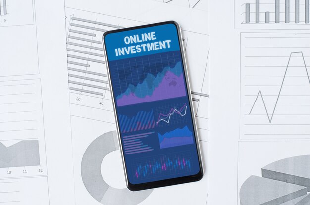 Online investment. Smartphone with a mobile app on the background of graphs and charts. Copy space.