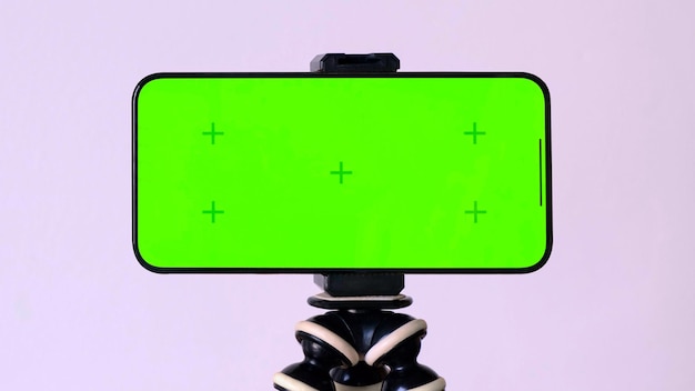 Photo online learning green screen of smartphone with vfx motion tracking markers on tripod at white backg