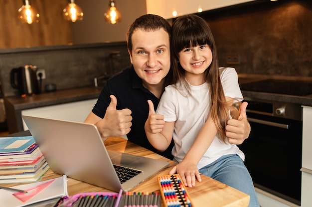 Online leren en samenhorigheid in het gezin. Gelukkig schoolmeisje en haar vader thuis. Afstandsonderwijs, thuisschool.