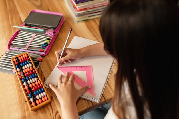 Online leren thuis. schoolmeisje met een laptop huiswerk. afstandsonderwijs tijdens quarantaine