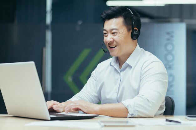 Online leren van jonge knappe mannelijke aziatische student die op afstand studeert met laptop en koptelefoon