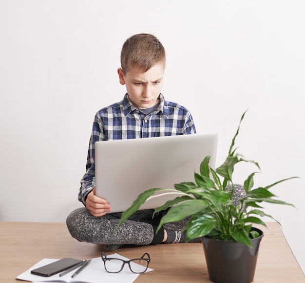 Online les thuis, sociale afstand tijdens quarantaine, zelfisolatie, online onderwijsconcept, thuisonderwijs. Jongen online taal leren, met behulp van laptop, onderwijs op afstand. Student jongen, school