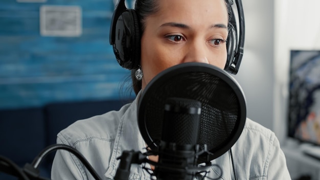 Online live radio talk show host filming remote podcast while\
talking to public at home studio desk. famous social media\
influencer sitting in living room while hosting video.