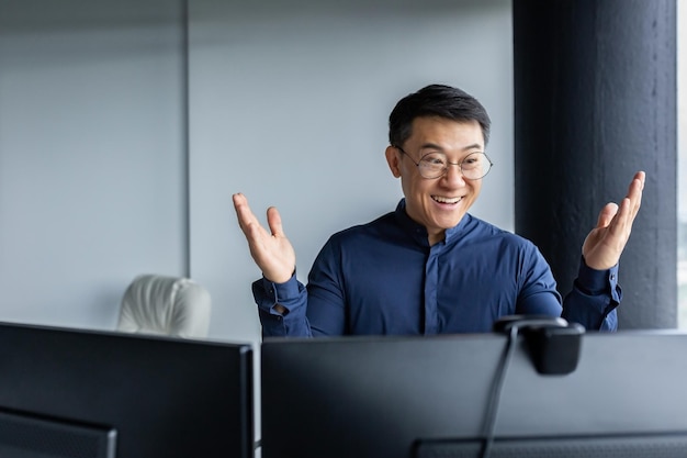 Online meeting with international partners a happy young asian businessman sits in a modern office