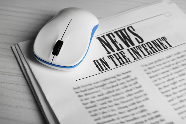 Online news concept computer mouse and newspaper on wooden
table background