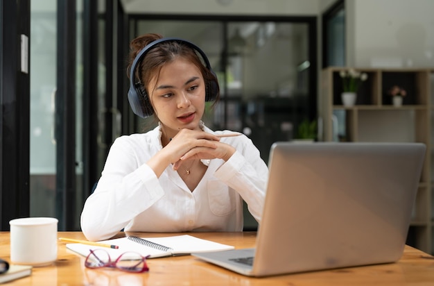 Online onderwijs e-learning jonge vrouw die op afstand studeert met behulp van een laptop die luistert naar online lezing die aantekeningen maakt terwijl ze thuis zit glimlacht