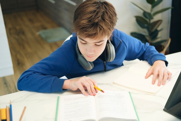 Online onderwijs op afstand. Een schooljongen studeert thuis en maakt huiswerk op school. Een thuisonderwijs op afstand.