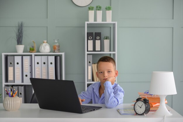 Online onderwijs op afstand Een schooljongen studeert thuis en maakt huiswerk op school