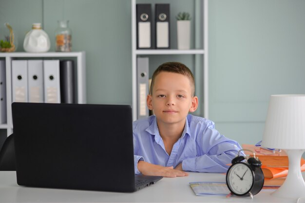 Online onderwijs op afstand Een schooljongen studeert thuis en maakt huiswerk op school