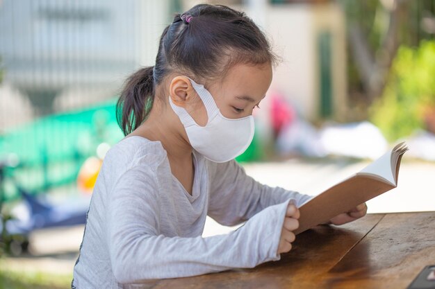 Online onderwijs op afstand. kind in een masker om een online les te kijken.