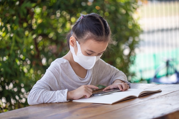 Online onderwijs op afstand. kind in een masker om een online les te kijken.