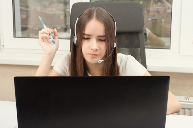 Online onderwijs Webinar Een student thuis is bezig met training luistert aandachtig en kijkt naar een lezing op een laptop met een microfoon in een koptelefoon