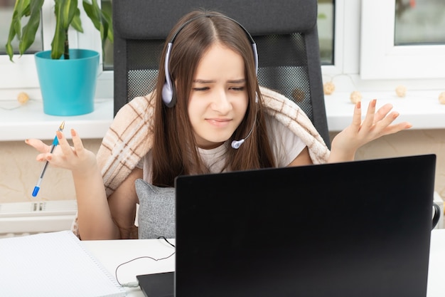 Online onderwijs. webinar. student thuis met microfoon in koptelefoon verontwaardigd voor de monitor