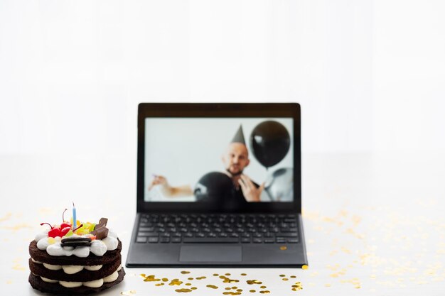 Online party birthday greeting festive celebration defocused man in holiday decor balloons on laptop