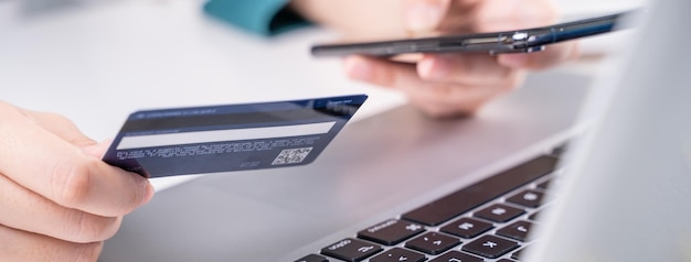 Фото Онлайн оплата покупок электронными платежами с помощью кредитной карты, смартфона, концепции ноутбука на фоне белого стола с тележкой для покупок крупным планом