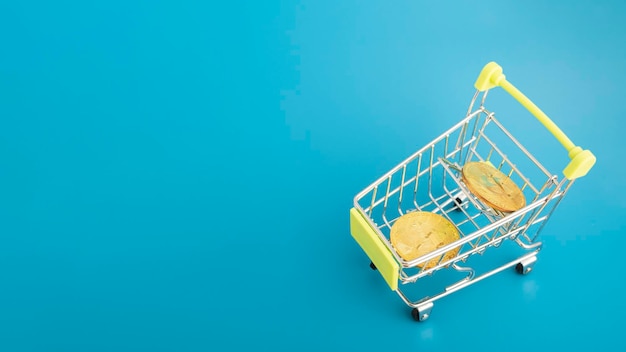 Online payment concept Cryptocurrency bitcoin in a shopping cart trolley on a blue background with copy space