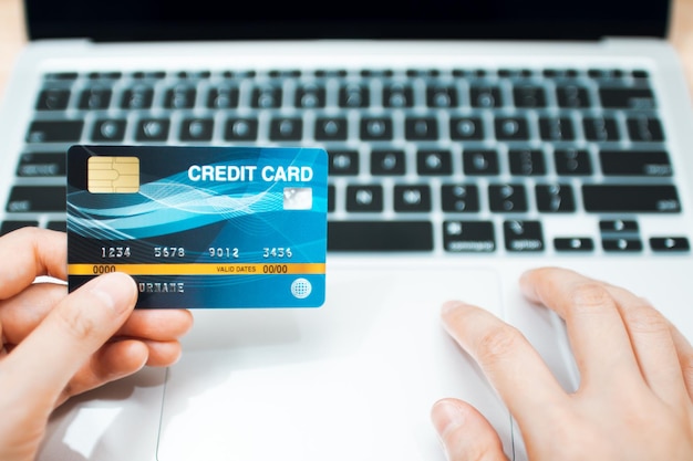 Online payment concept. Hand holding a credit card and using laptop for online shopping.