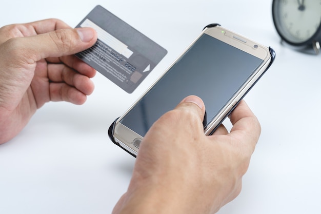 Photo online payment concept. man using credit card and office desk table with computer, clock