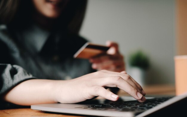 Online payment digital banking woman hand using credit card for online shopping via laptop computer on table