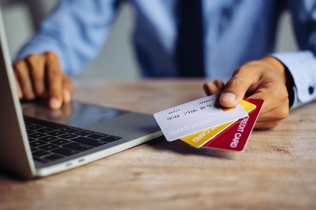 Руки онлайн-платежей держат кредитную карту и используют ноутбук Концепция онлайн-покупок