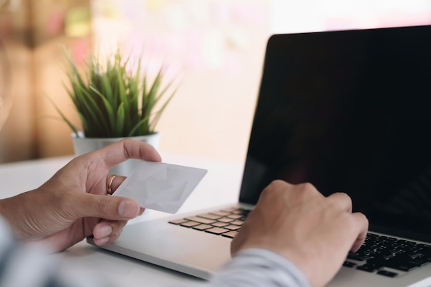 Pagamento online, le mani dell'uomo che tengono smartphone e utilizzando la carta di credito per lo shopping online.