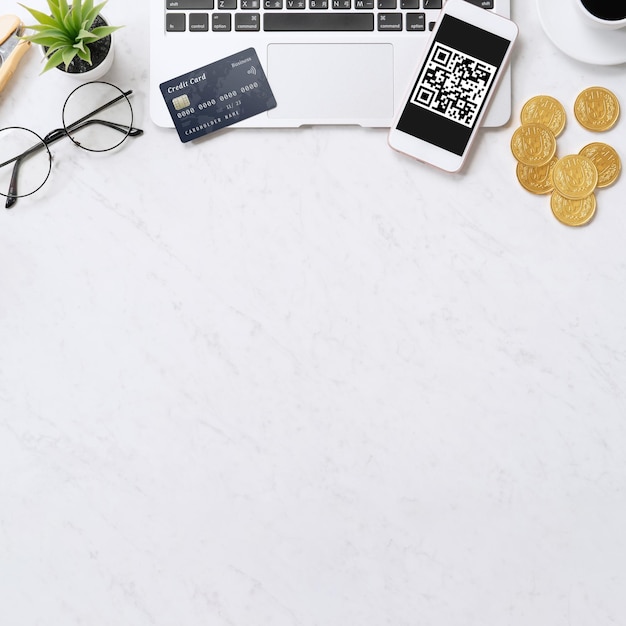 Online payment with QR code concept virtual credit card smart phone on office laptop desk on clean marble table background top view flat lay