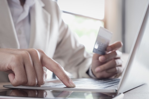 Foto pagamento online, la mano del giovane che utilizza il computer portatile e la carta di credito della tenuta della mano per lo shopping online.