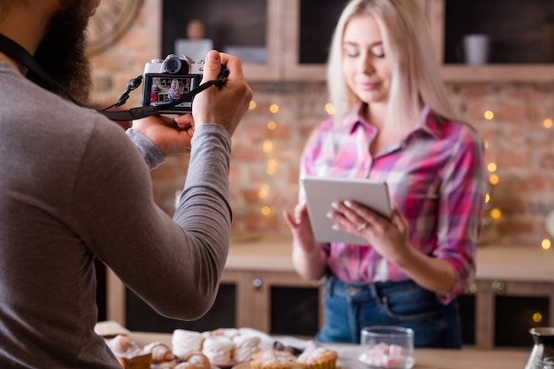 Online recipe. Blogging. Woman with tablet. Man shooting vlog episode on cakes and pastries cooking.