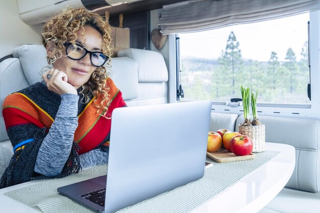 Online remote worker using laptop inside a modern camper van living vanlife and wanderlust adventure travel lifestyle Digital nomad concept Living off grid people Nature view outside the window