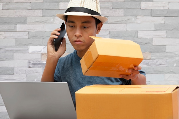 Online sales ideas for small business SME, Asian man using a smartphone taking checking online purchase shopping order.