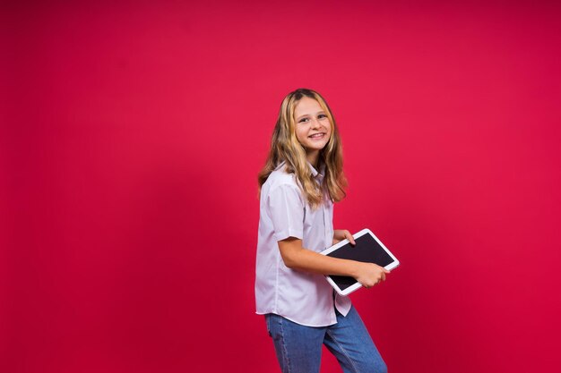 Online school app Schoolgirl showing tablet computer Empty Screen Over red Background Studio Shot