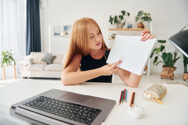 Online school Female teenager with blonde hair is at home at daytime